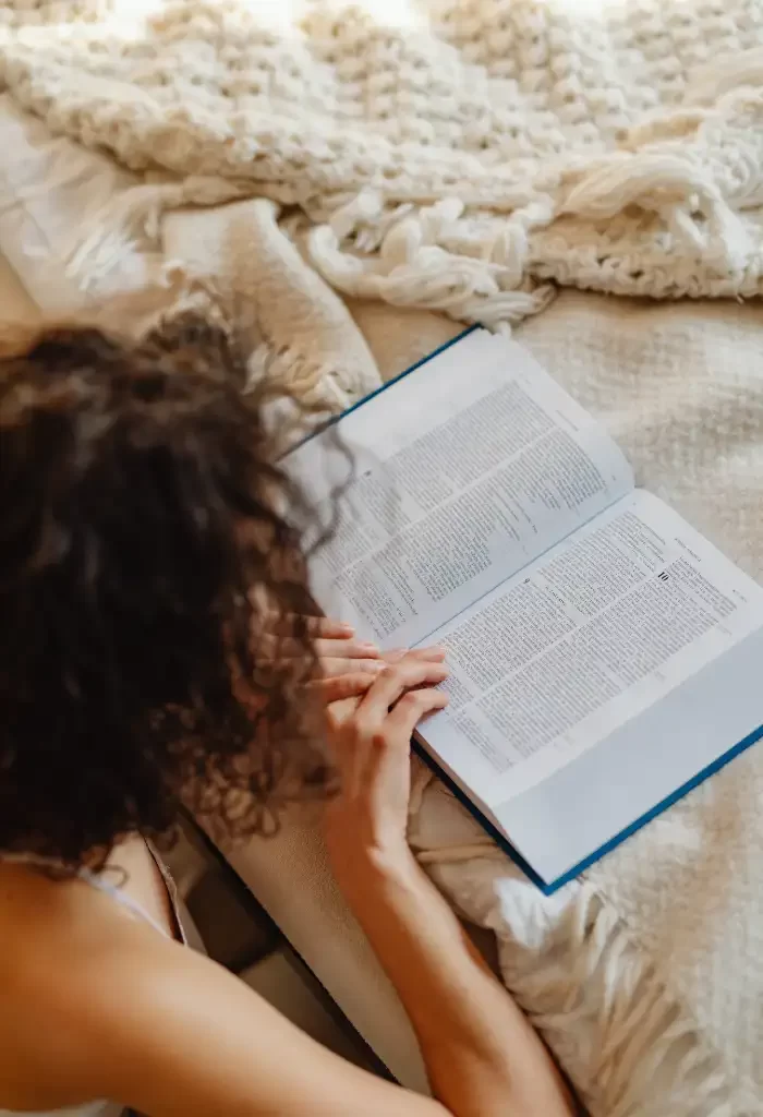 Una mujer leyendo un libro en la cama.